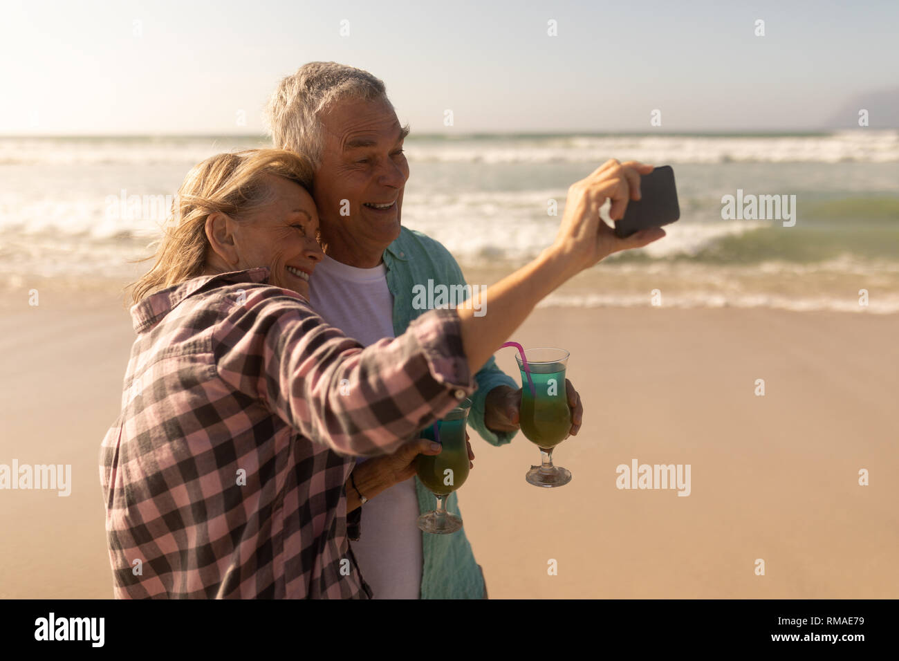 Senior Paar unter selfie mit Mobiltelefon, während mit Cocktail am Strand Stockfoto