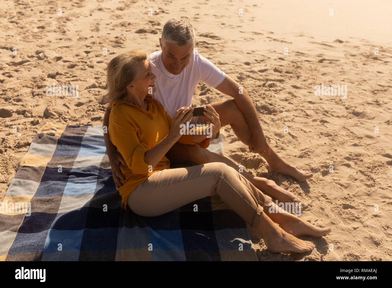 Senior paar Überprüfung durch Fotos auf Handy am Strand Stockfoto