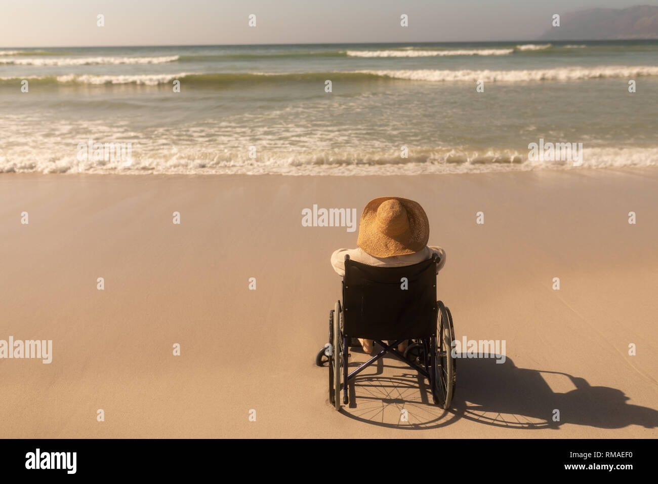Behinderte ältere Frau am Meer am Strand Stockfoto