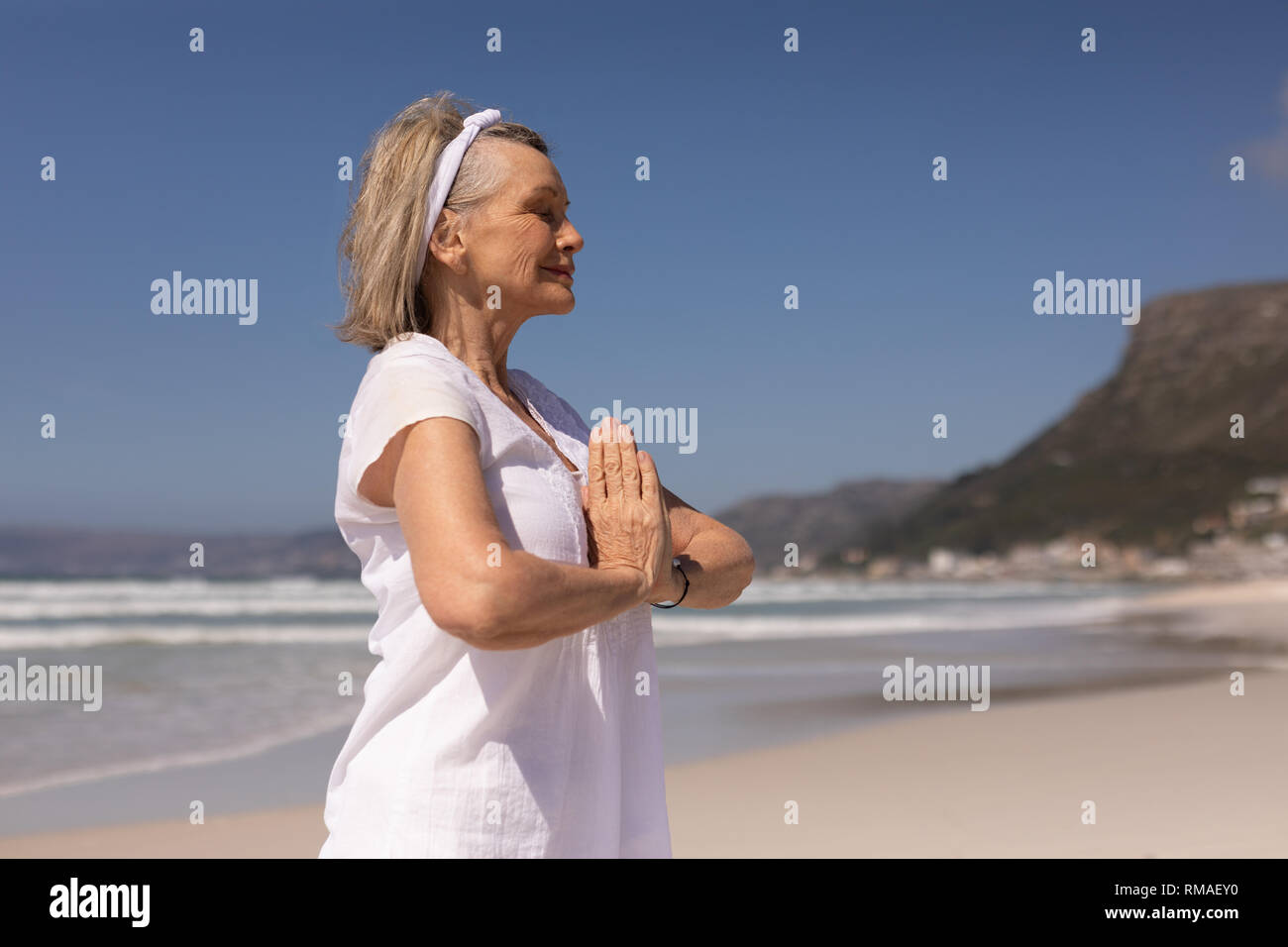 Seitenansicht der älteren Frau, meditieren im Gebet Position am Strand Stockfoto