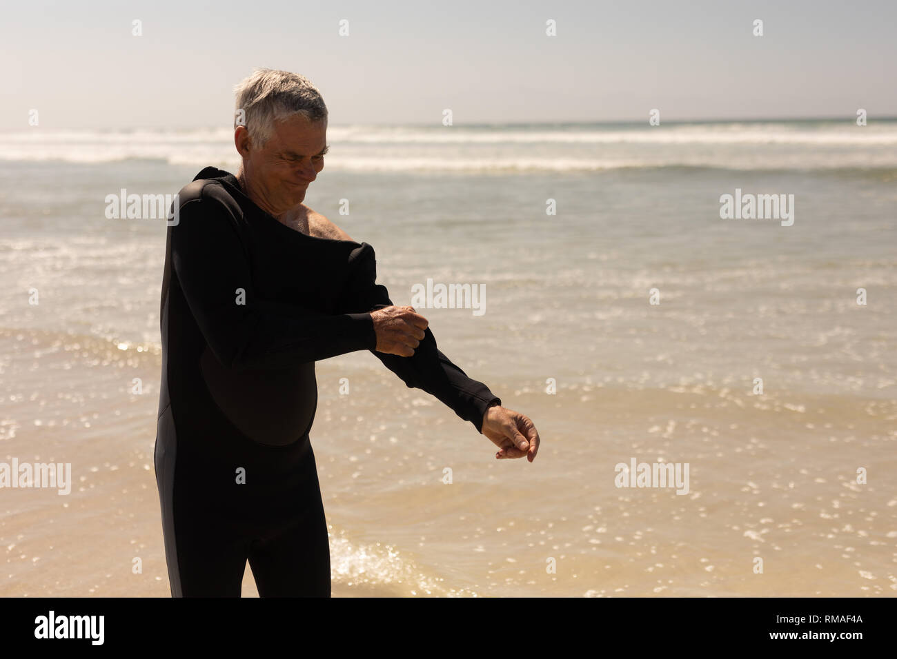 Seitenansicht der älteren männlichen Surfer tragen Anzug am Strand Stockfoto