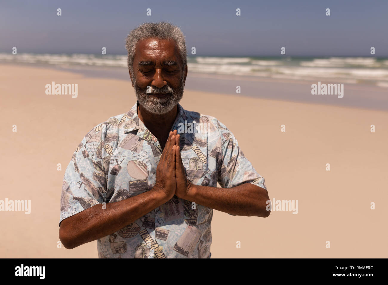 Älteren schwarzen Mann mit gefalteten Händen beten am Strand Stockfoto