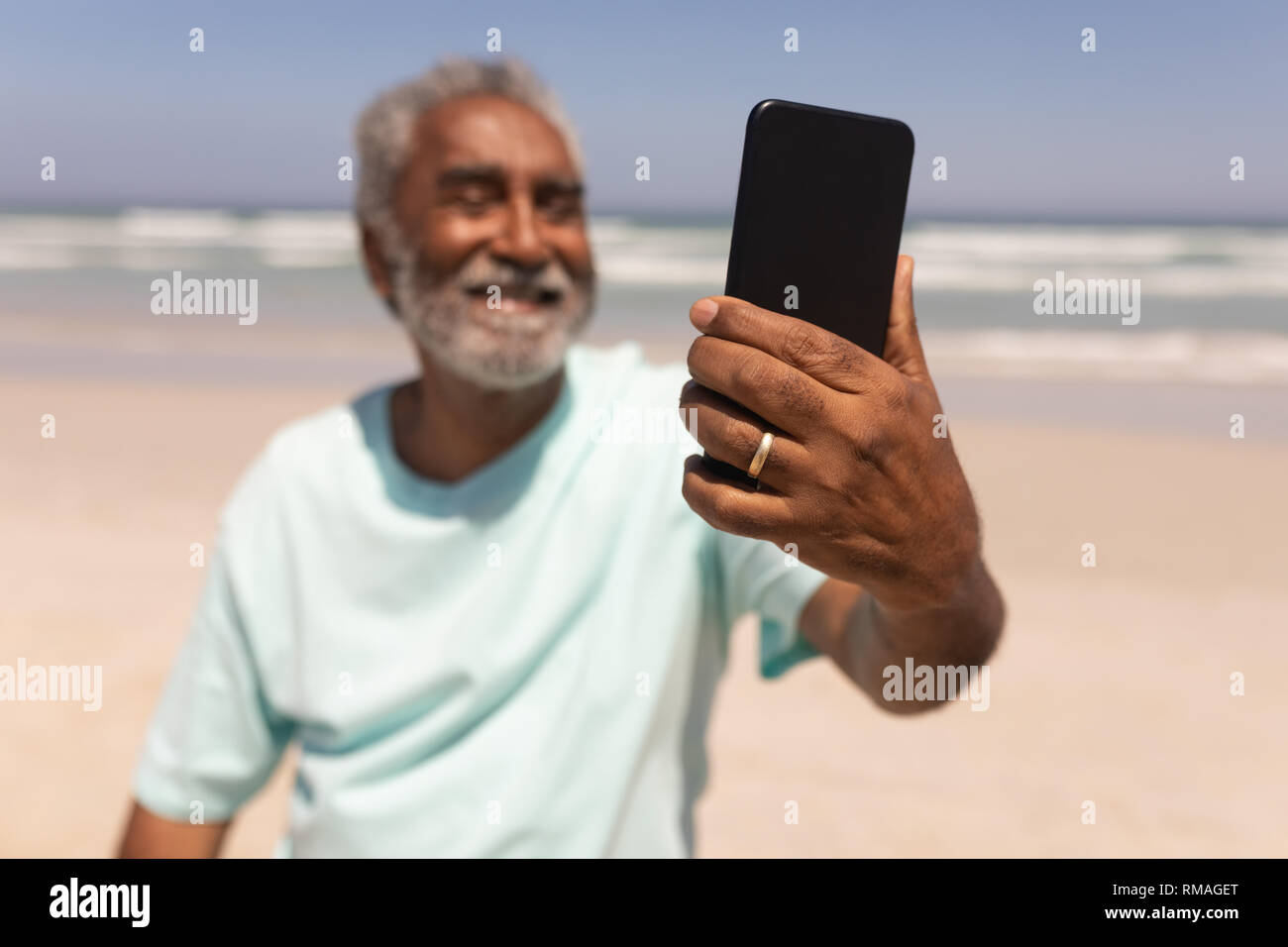 Älterer Mann selfie mit Handy am Strand Stockfoto