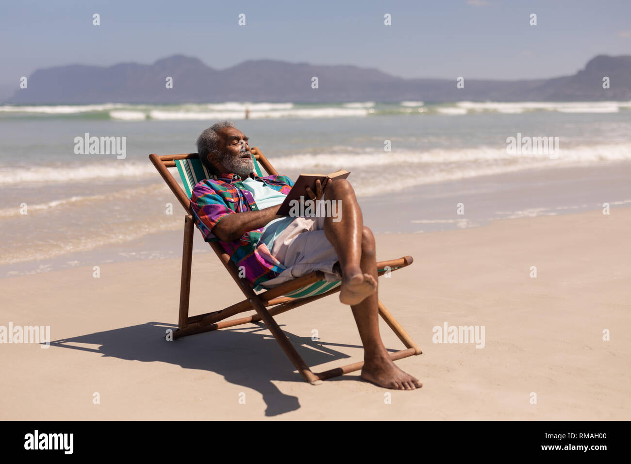 Ältere Menschen entspannend auf Sonnenliege und ein Buch lesen am Strand Stockfoto