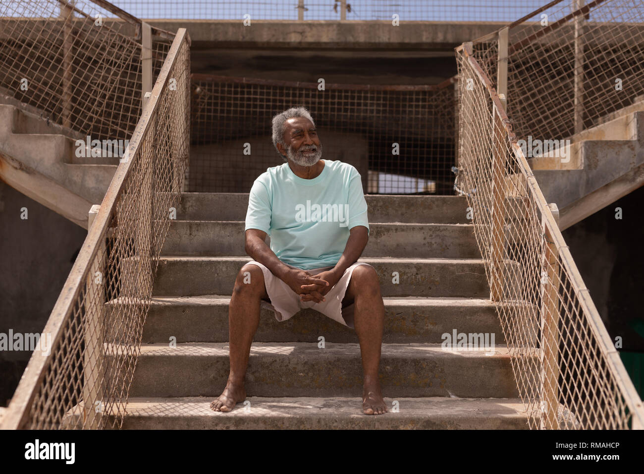 Älterer Mann sitzt auf der Promenade Treppen an den Strand Stockfoto