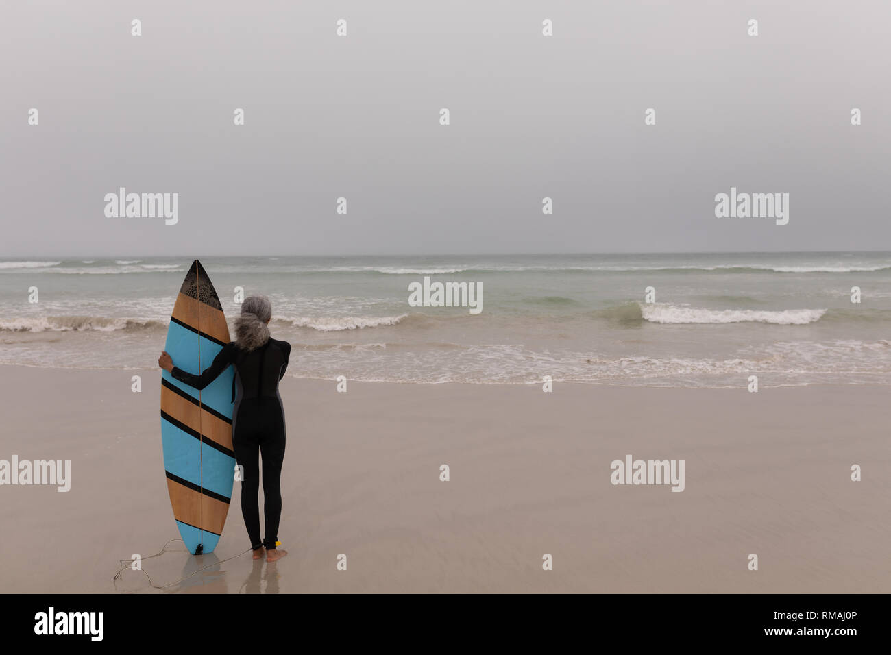 Ältere weibliche Surfer mit Surfbrett stehend auf den Strand Stockfoto