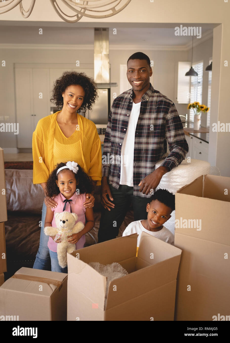 Gerne Afrikanische amerikanische Familie mit Kartons an Kamera suchen im Wohnzimmer Stockfoto