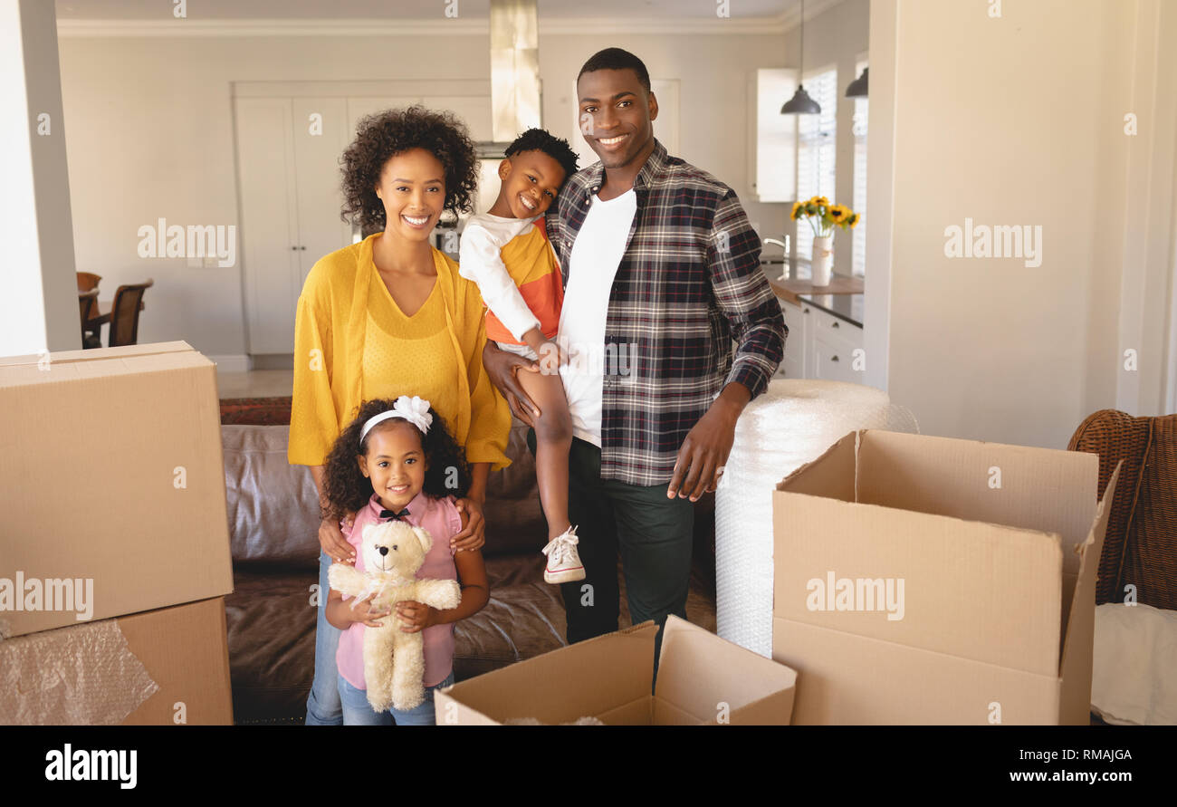Gerne Afrikanische amerikanische Familie mit Kartons an Kamera suchen im Wohnzimmer Stockfoto