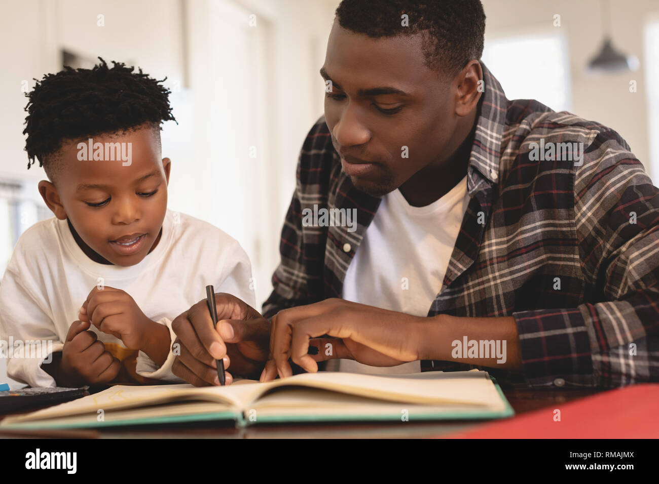 African American Vater seinen Sohn helfen bei Hausaufgaben am Tisch Stockfoto