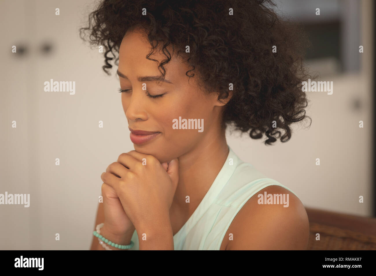 Afrikanische amerikanische Frau mit der Hand umklammert und geschlossenen Augen beten am Esstisch Stockfoto