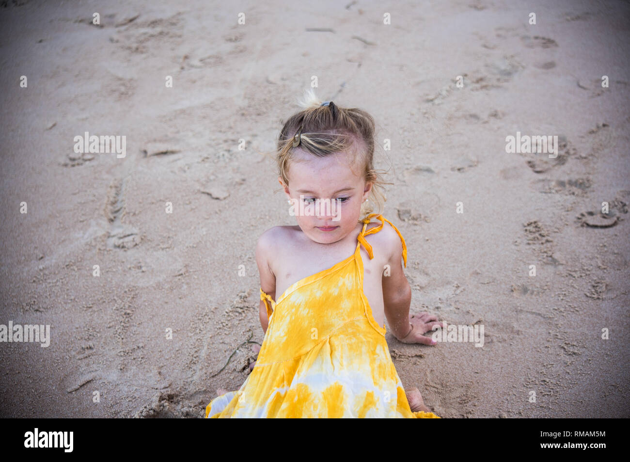 Kleine blonde Kind im sand sitzen Stockfoto
