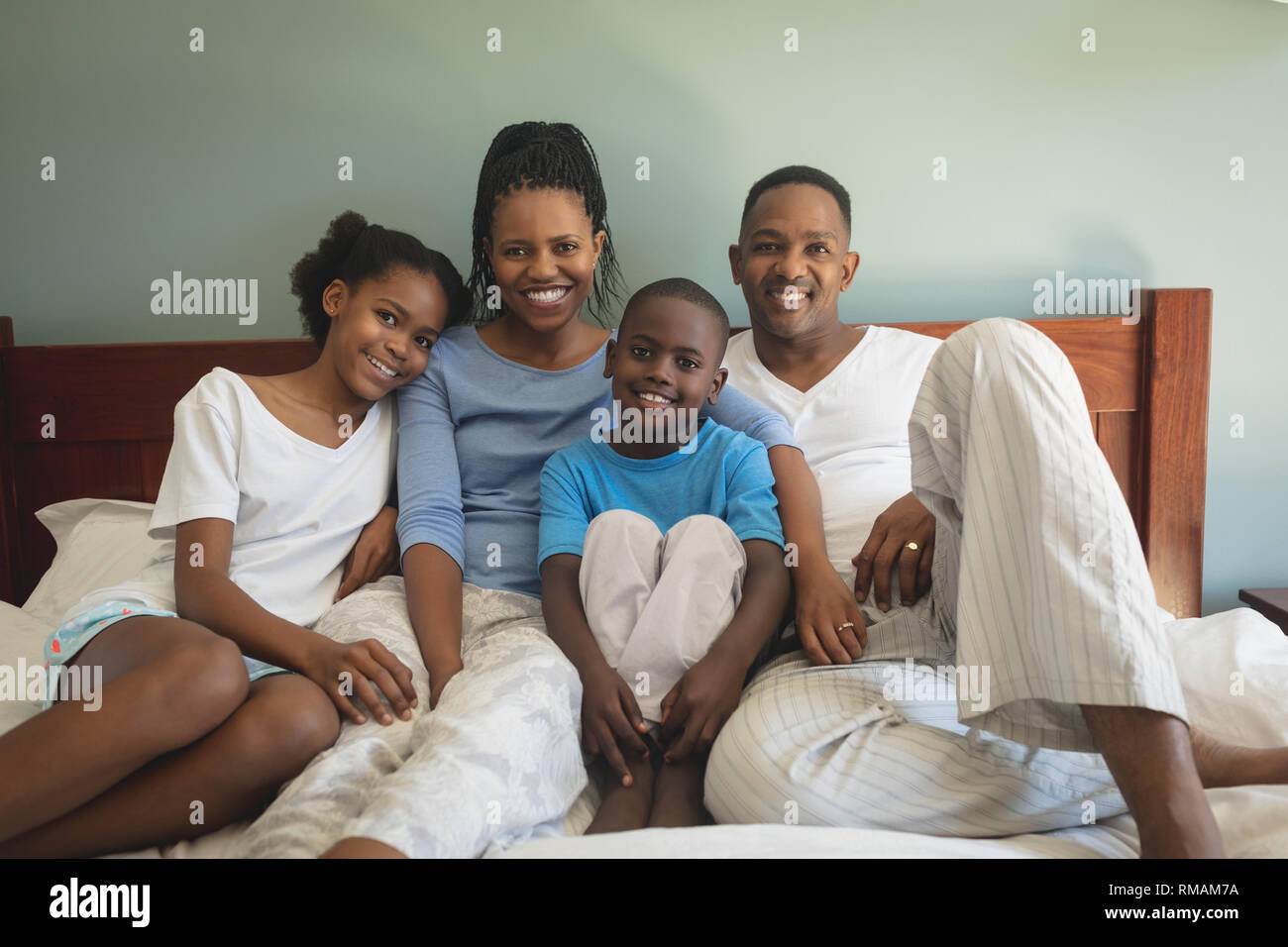 Gerne Afrikanische amerikanische Familie, die von der Kamera, während sie sich auf dem Bett im Schlafzimmer Stockfoto