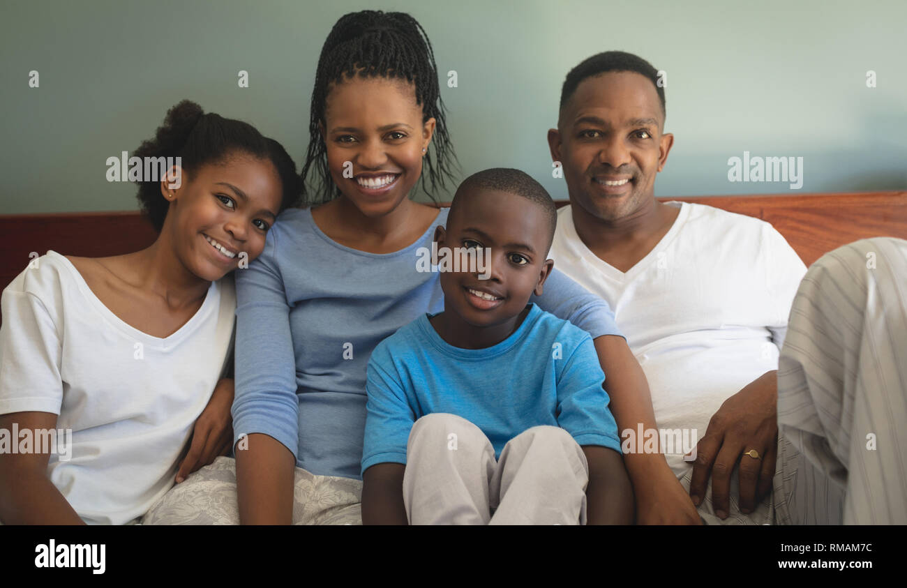 Gerne Afrikanische amerikanische Familie, die von der Kamera, während sie sich auf dem Bett im Schlafzimmer Stockfoto