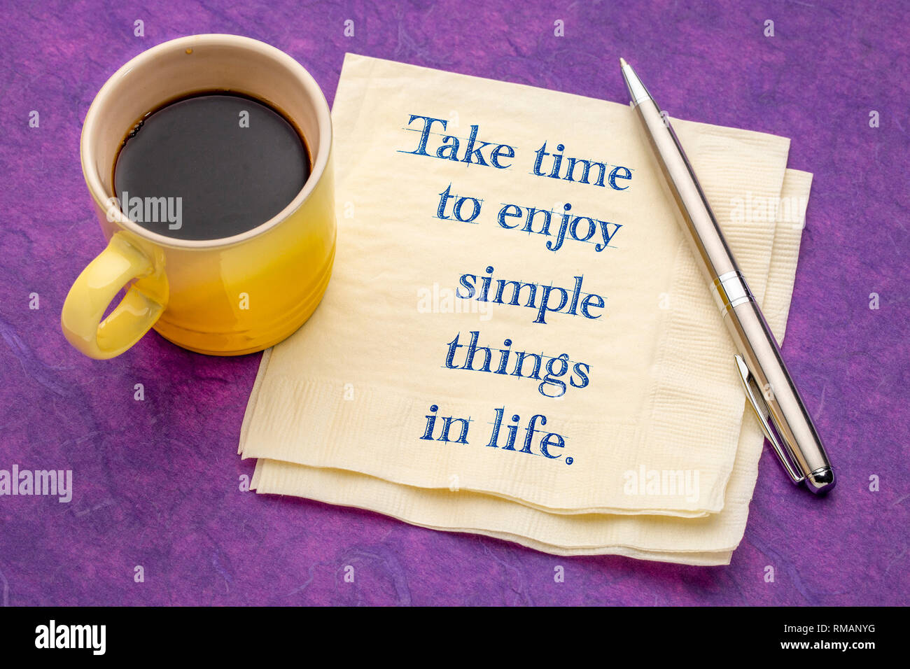 Nehmen Sie sich Zeit, die einfachen Dinge des Lebens zu genießen - Handschrift auf eine Serviette mit einer Tasse Kaffee gegen bunte strukturiertes Papier Stockfoto