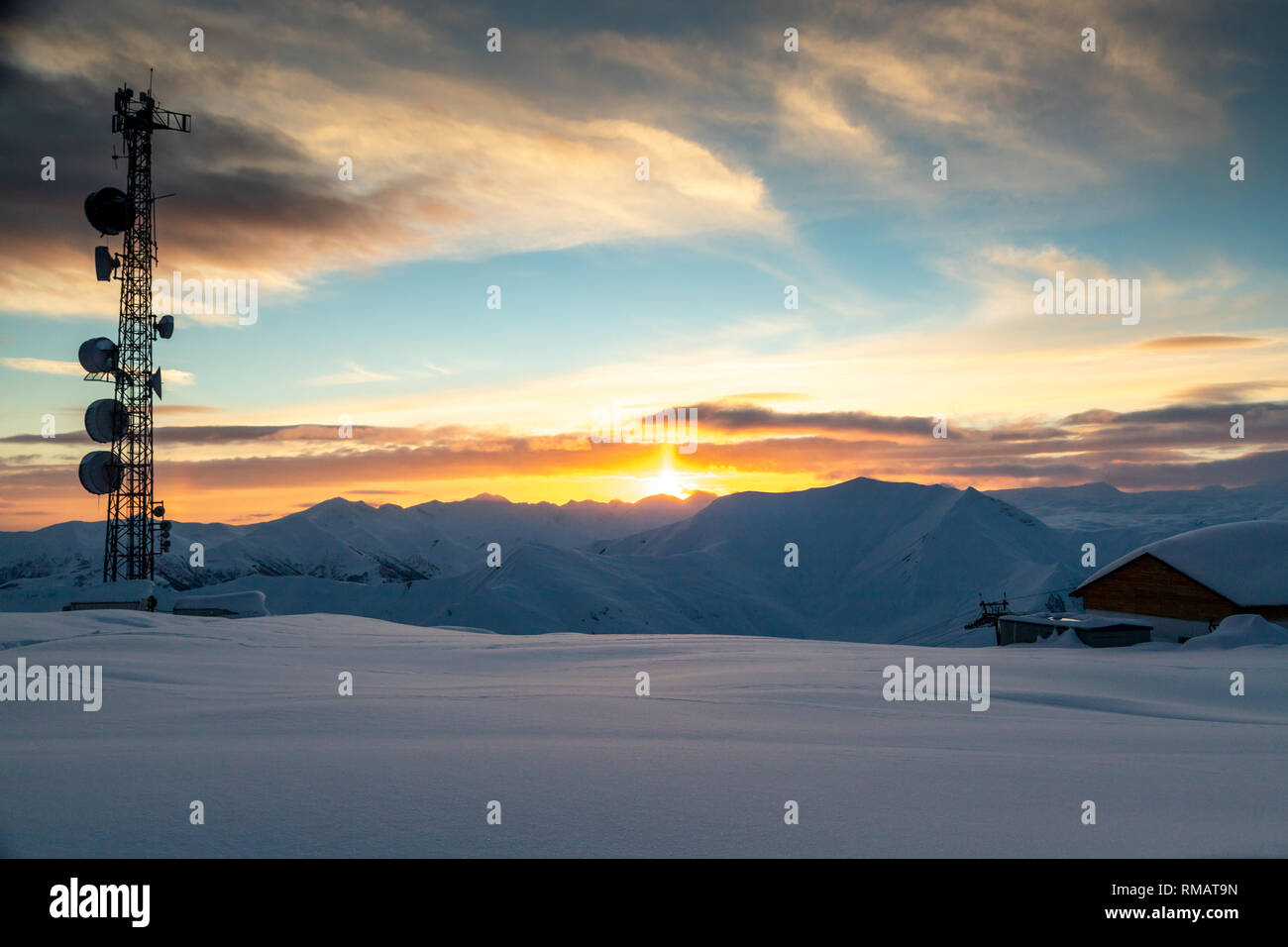 Kommunikation Turm mit Antennen und Satellitenschüsseln im Hintergrund einer winterlichen Bergwelt, bei Sonnenuntergang. Gudauri, Georgien Stockfoto