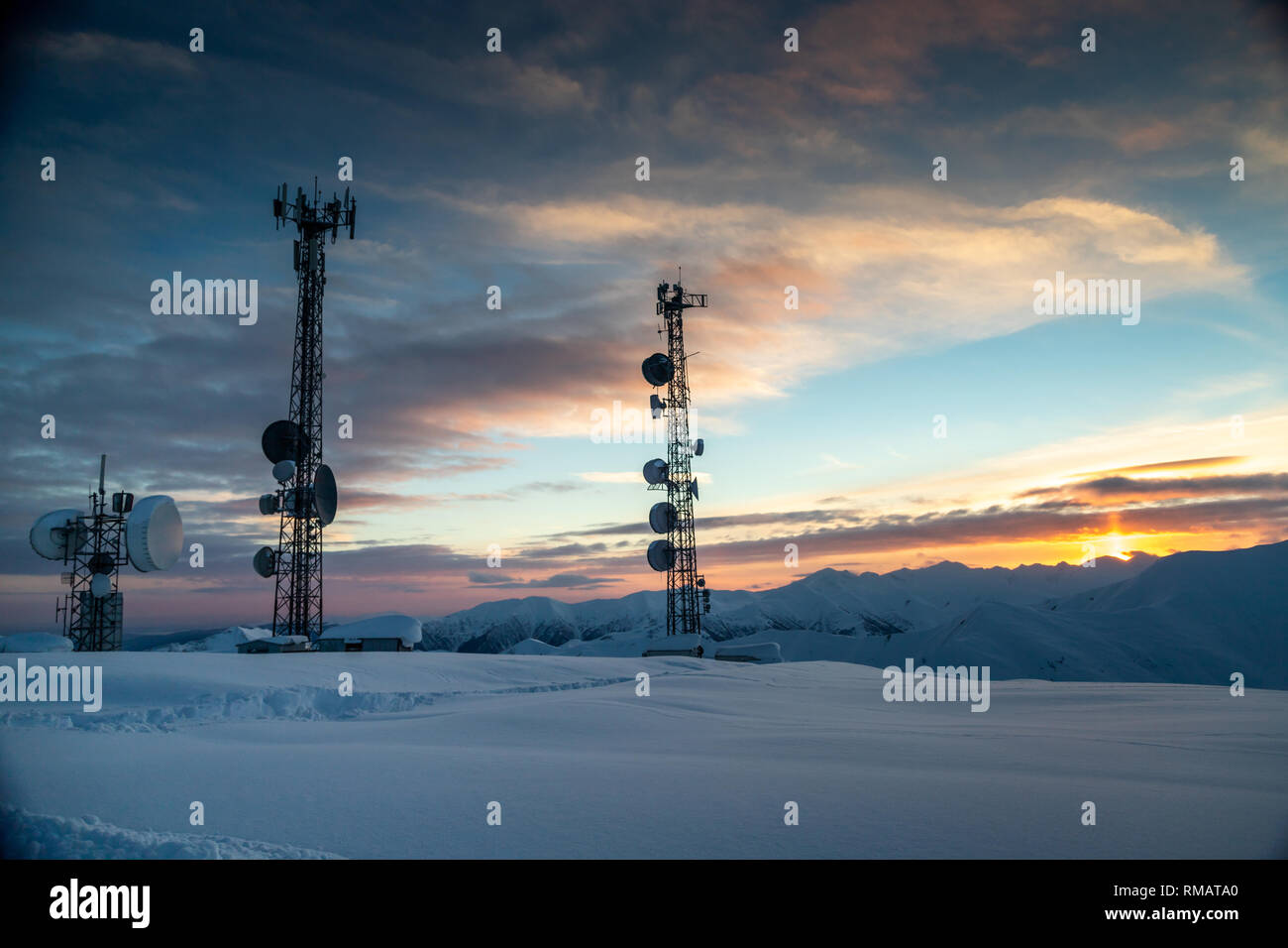Kommunikation Turm mit Antennen und Satellitenschüsseln im Hintergrund einer winterlichen Bergwelt, bei Sonnenuntergang. Gudauri, Georgien Stockfoto