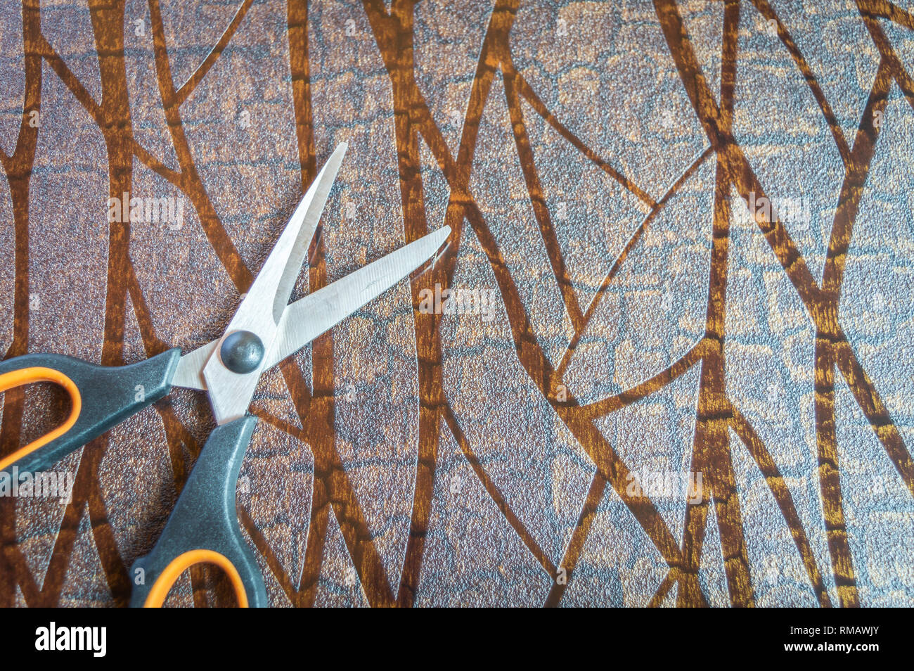 Blick von oben auf eine Schere auf einer strukturierten braun Tabelle gehalten. Kopieren Sie Speicherplatz zur Verfügung Stockfoto