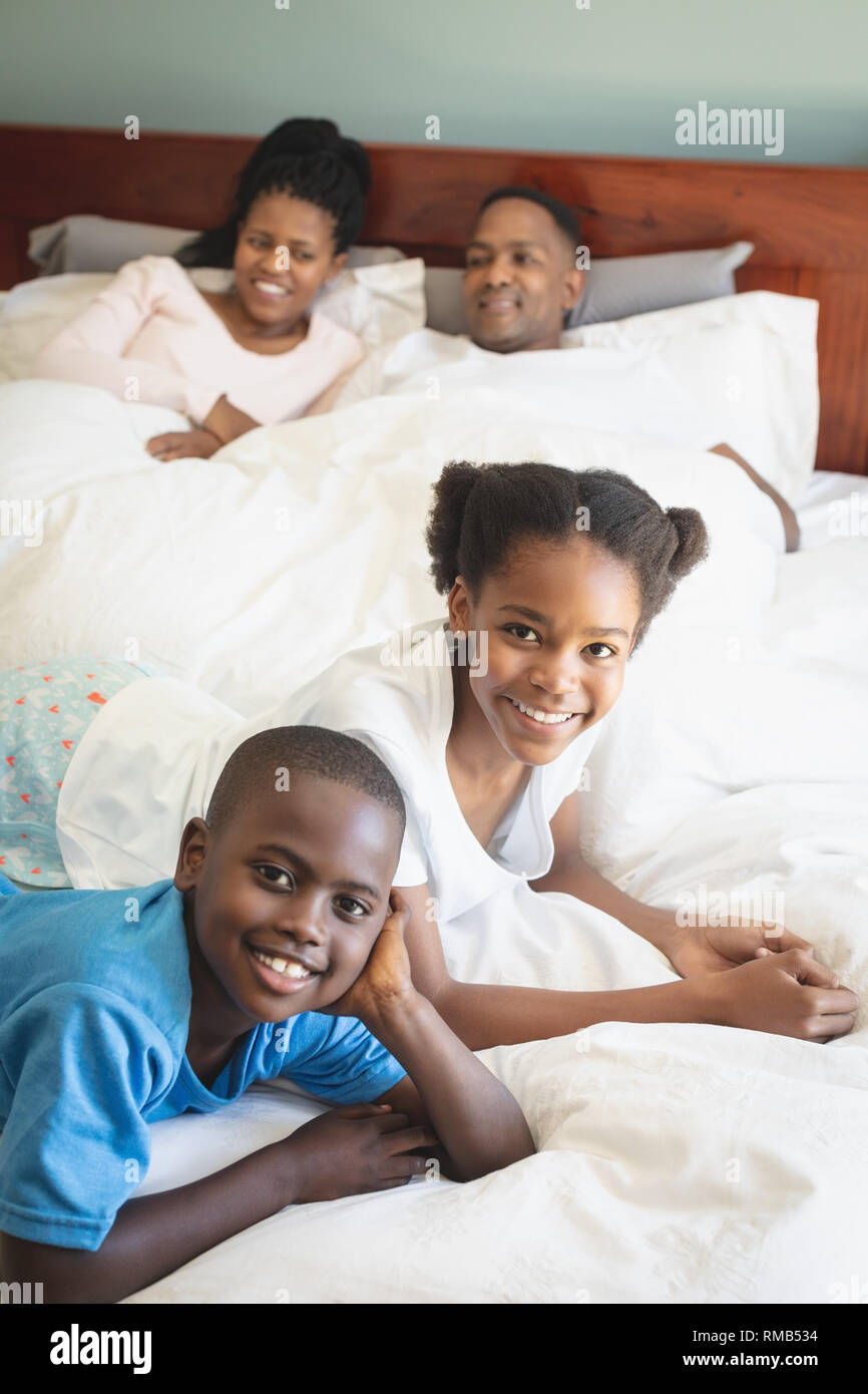 Gerne Afrikanische amerikanische Familie, die von der Kamera, während sie sich auf dem Bett im Schlafzimmer Stockfoto