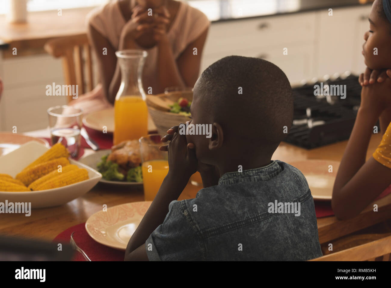 Afrikanische amerikanische Familie, die zusammen betet am Esstisch Stockfoto