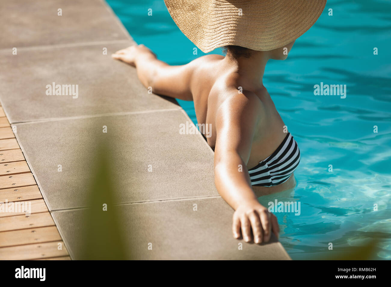 Junge mixed-race Frau mit Hut schiefen am Rande von Pool Stockfoto