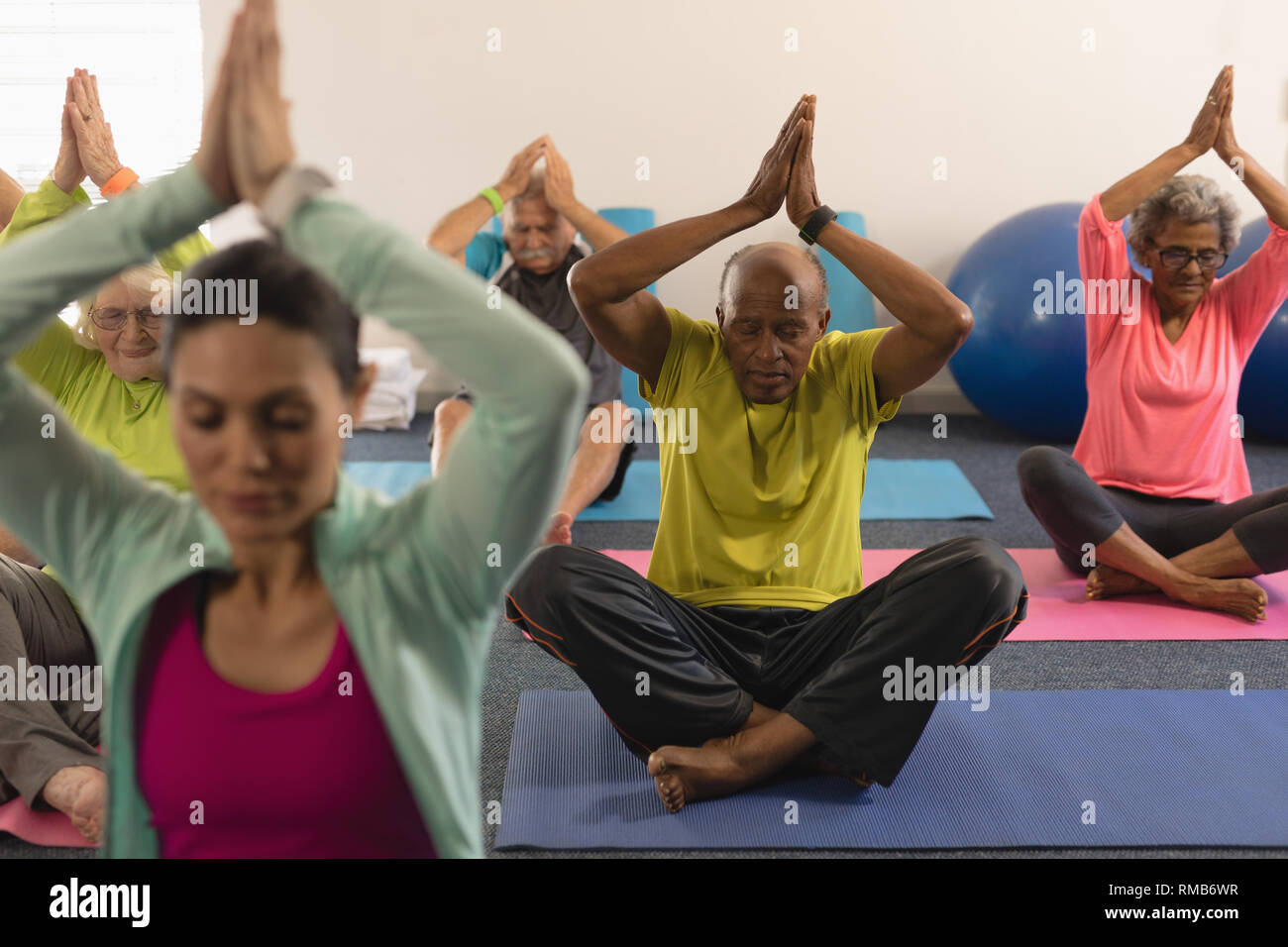 Ältere Menschen, die Yoga mit weiblichen Trainer im Fitness Studio. Stockfoto