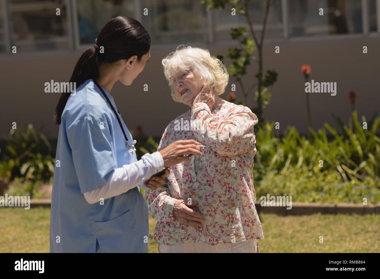 Junge Ärztin untersuchen ältere Frau im Garten Stockfoto