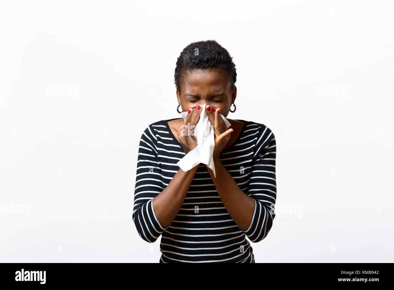 Junge afrikanische Frau, die ihre Nase weht auf einem Gewebe konzeptionelle der saisonalen Grippe, Schnupfen oder eine respiratorische Allergie wie Heuschnupfen isoliert auf weißem Stockfoto