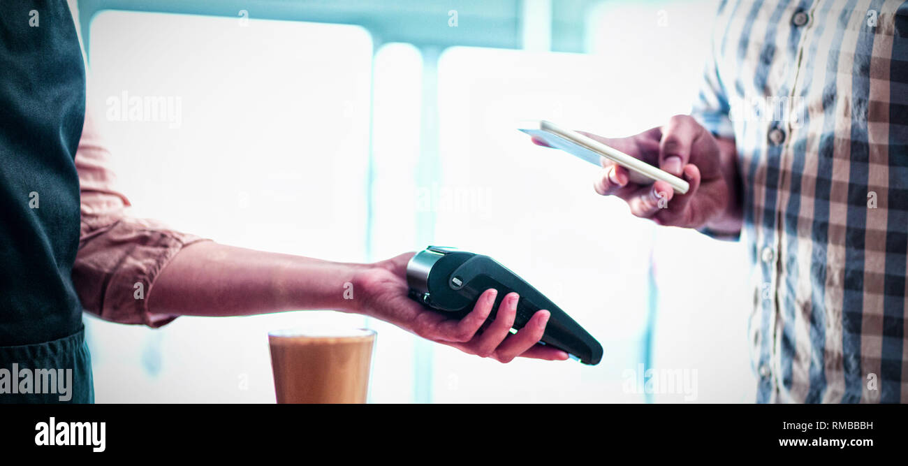 Mann, der Zahlung durch die NFC-Technologie im Cafe Stockfoto