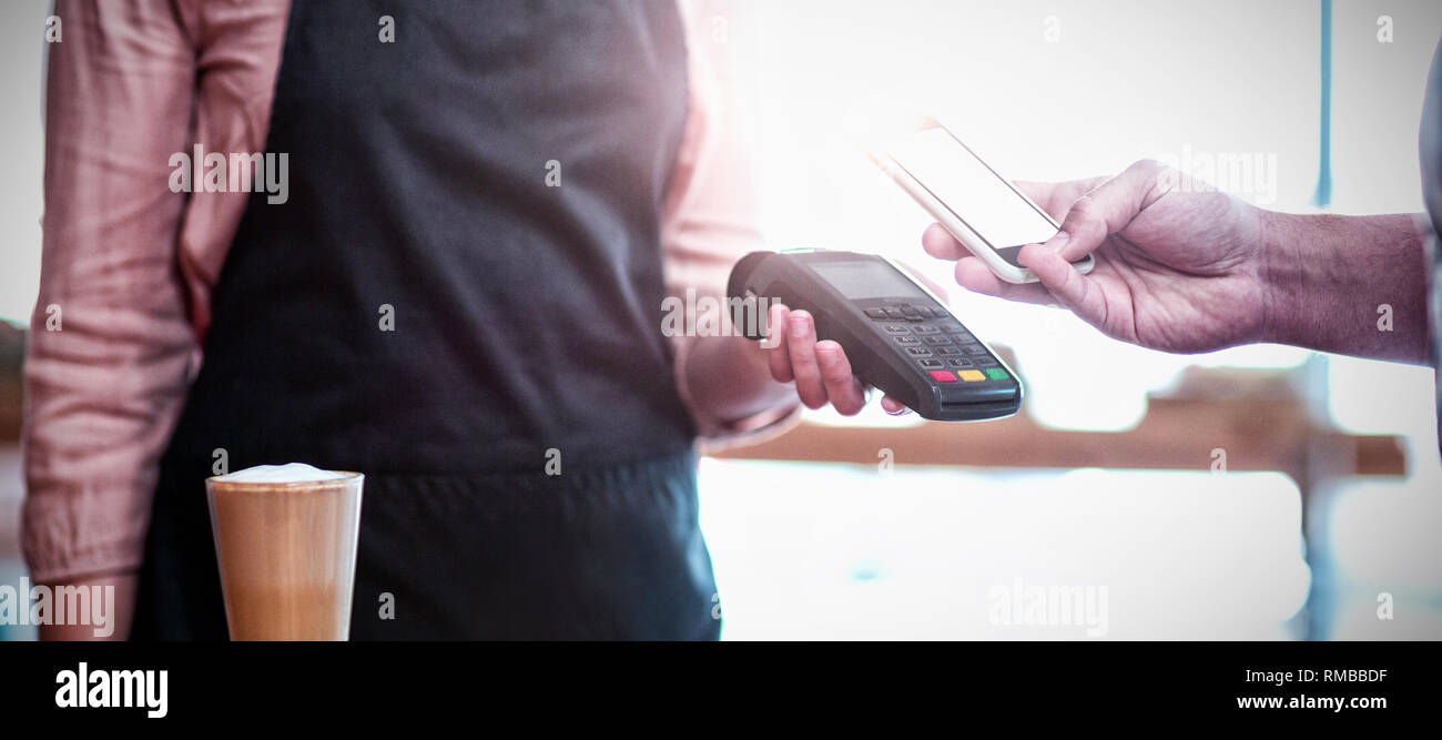 Mann, der Zahlung durch die NFC-Technologie im Cafe Stockfoto