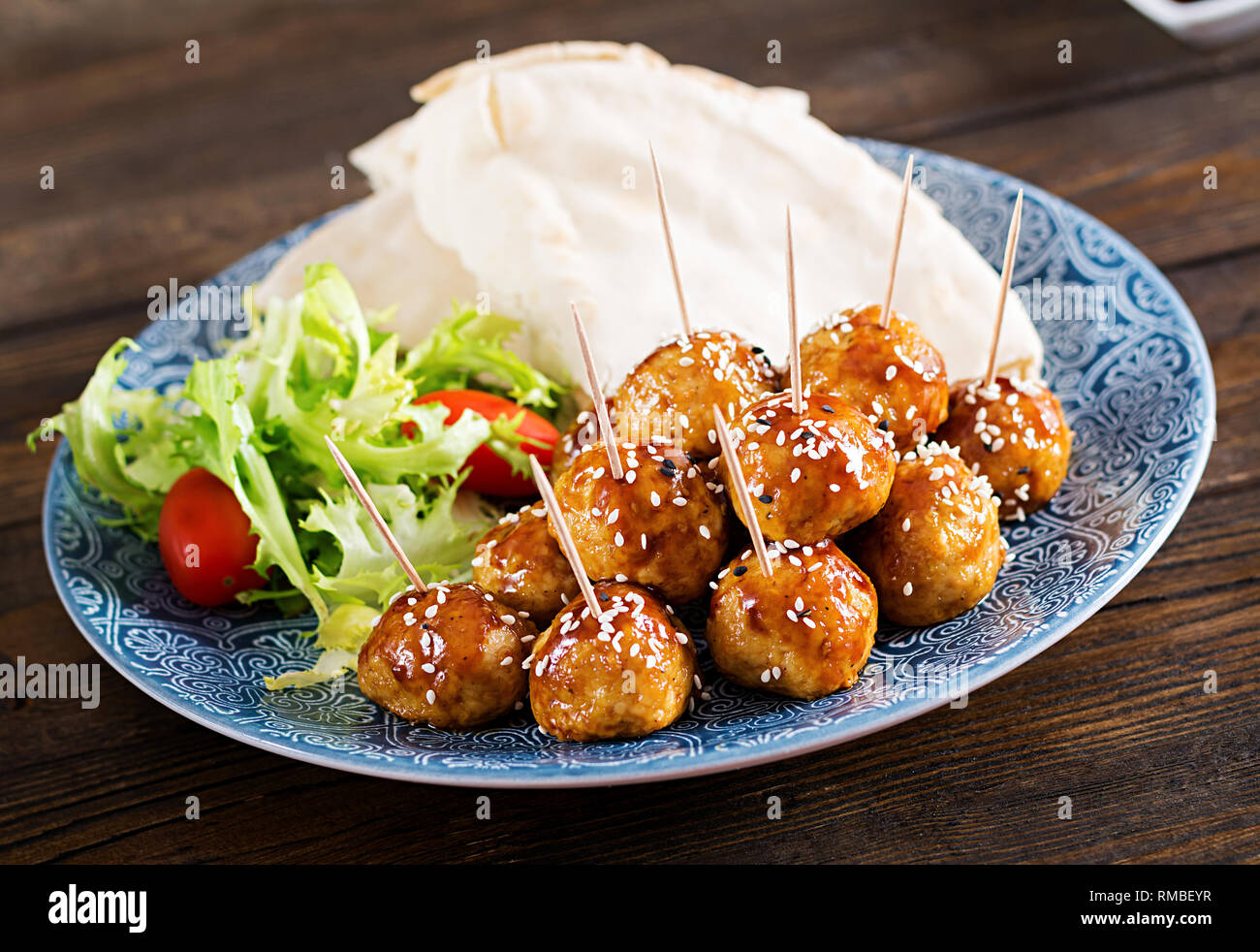 Fleischbällchen in süß und sauer auf einem Teller mit pita Brot und Gemüse Glasur im marokkanischen Stil auf einem Holztisch. Tapas. Trend essen. Stockfoto