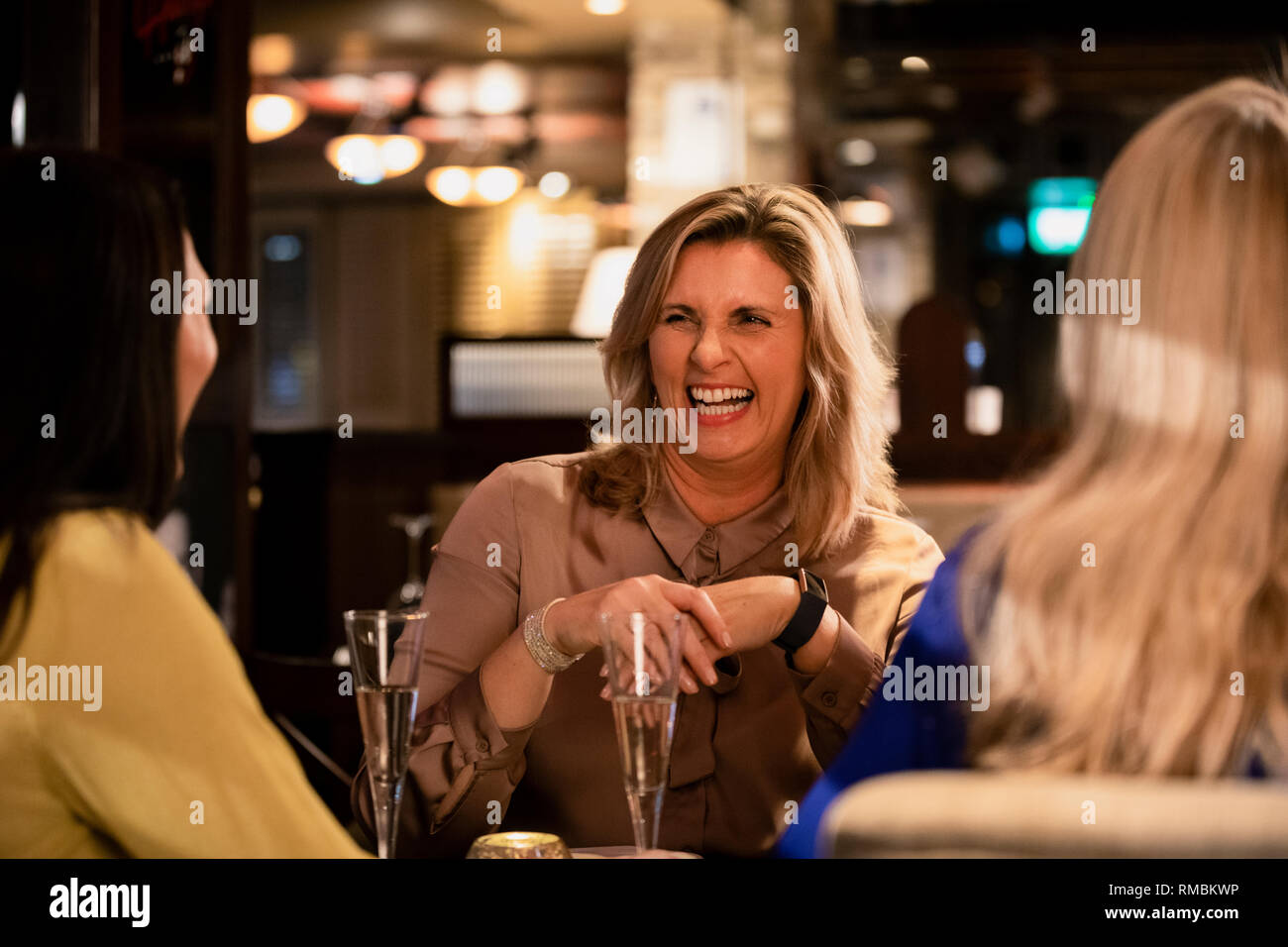 Über der Schulter auf eine reife Frau Lachen und Lächeln mit ihren Freunden in einem Restaurant sitzen. Stockfoto