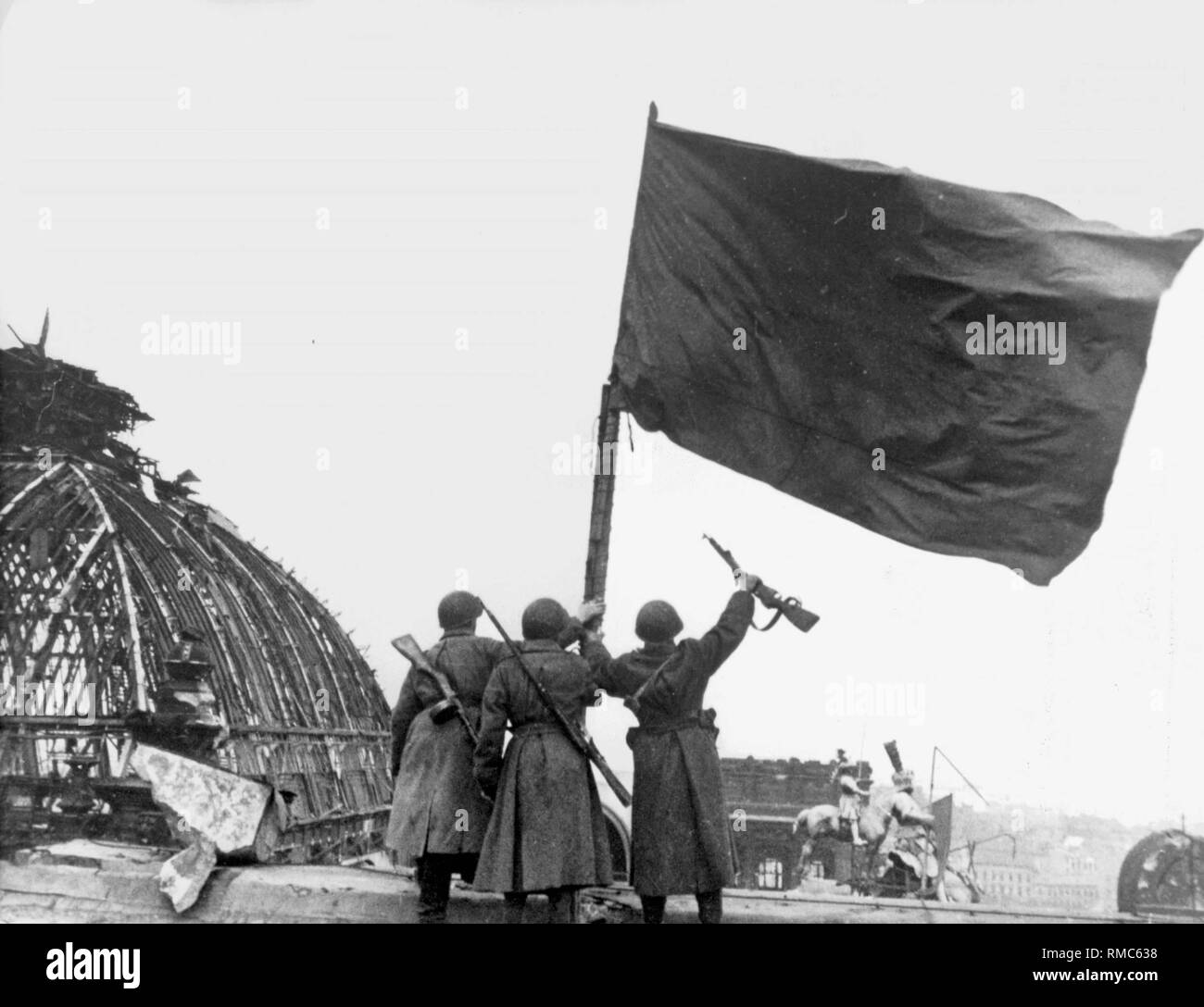 Soldaten der Roten Armee mit der Flagge der Sowjetunion auf dem Dach des zerstörten Reichstag und ihren Sieg feiern. Stockfoto