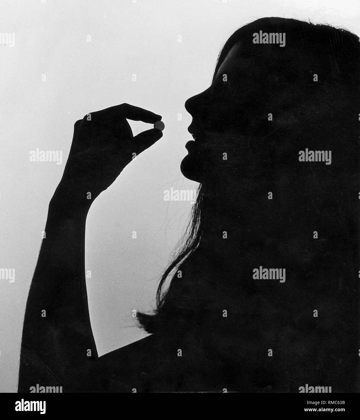 Eine junge Frau nimmt die Pille. Stockfoto