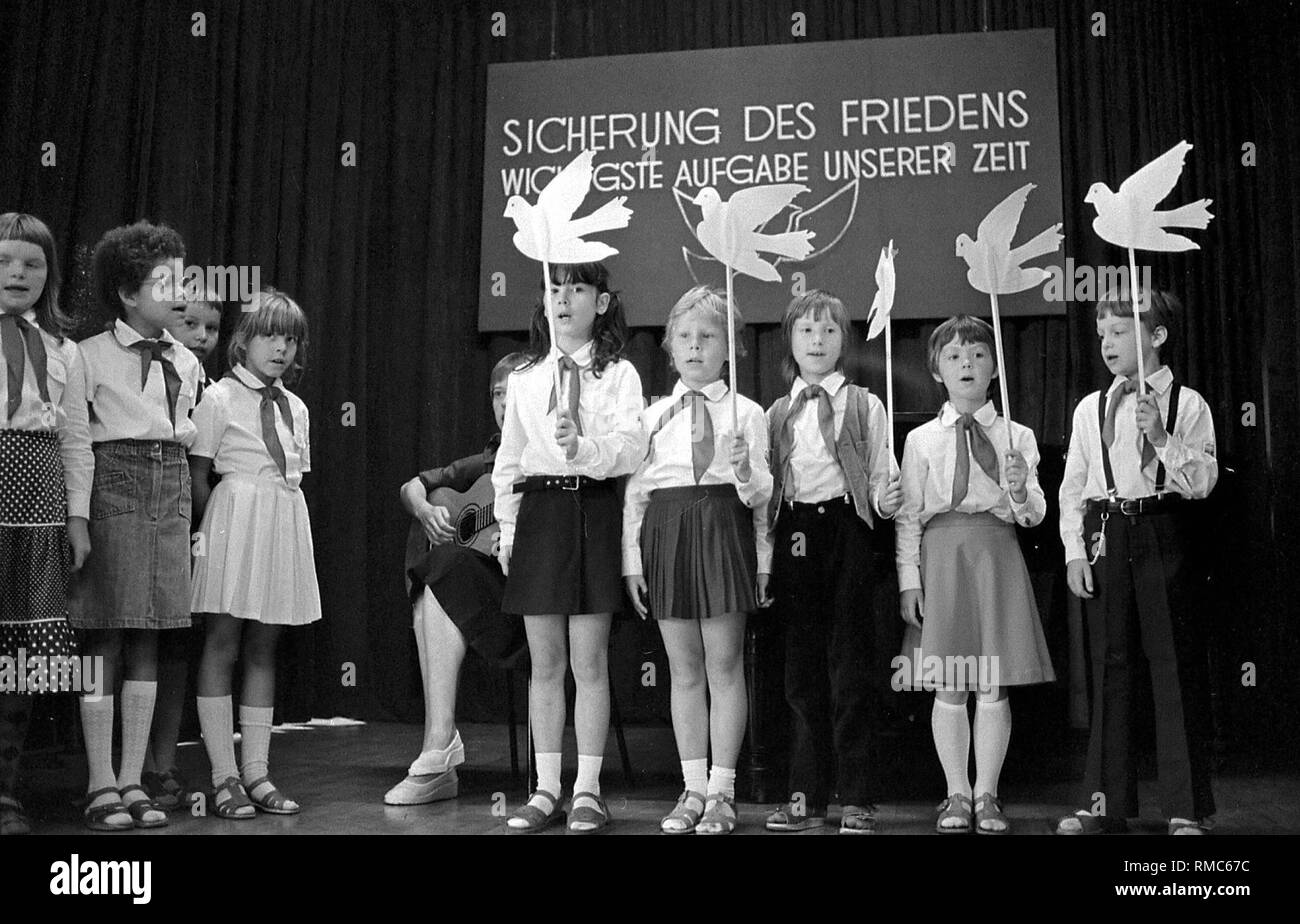 Ein Auftritt von Pionieren in Uniform und mit Frieden Tauben in den Händen, im Hintergrund ein Schild mit der Aufschrift ecuring Frieden, die wichtigste Aufgabe unserer Zeit". Stockfoto