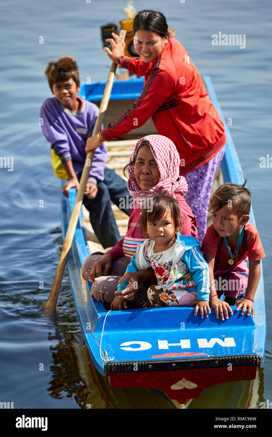 Tonlé Sap See, Kambodscha. 19. Dezember, 2017. Frauen und Kinder in ihre figerglass roat, während eine andere Frau steht und Zeilen. Foto: BryanWatt Stockfoto