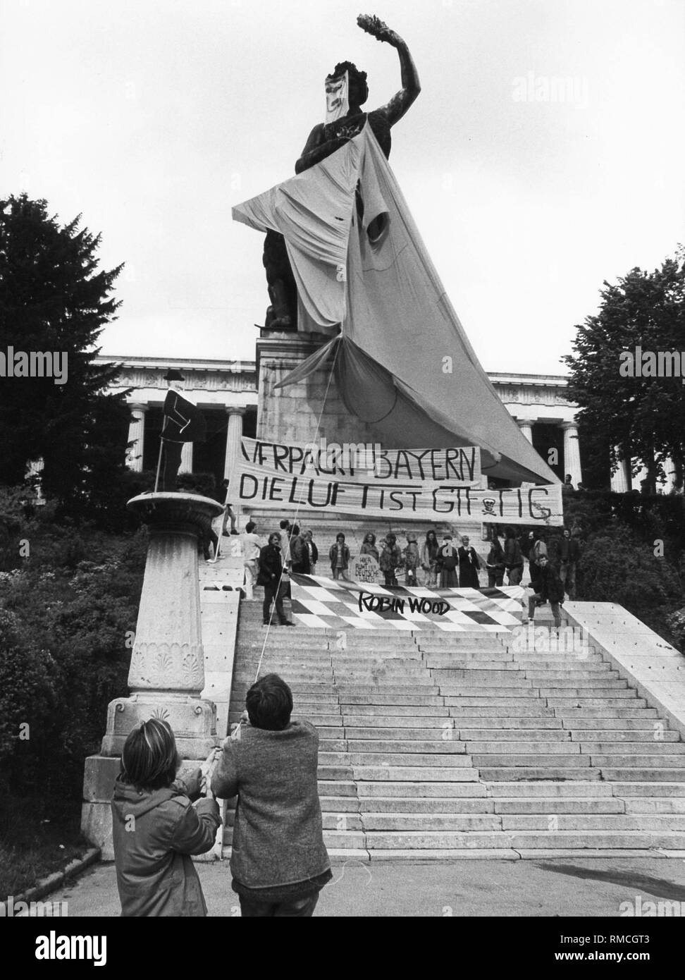 Aktivisten der Umweltschutzorganisation Robin Wood an der Bavaria auf der Theresienwiese in München mit einer Aktion, die mit der Luftverschmutzung zeigen sollte: "Wrap-up Bayern, die Luft ist giftig". Stockfoto