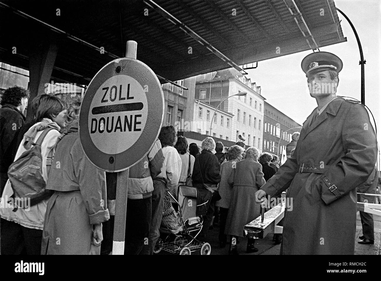 Am Grenzübergang Invalidenstraße in Ost Berlin, Bürger ziehen hinter einem Grenzsoldaten der DDR in den westlichen Teil der Stadt nach dem Fall der Berliner Mauer. Stockfoto
