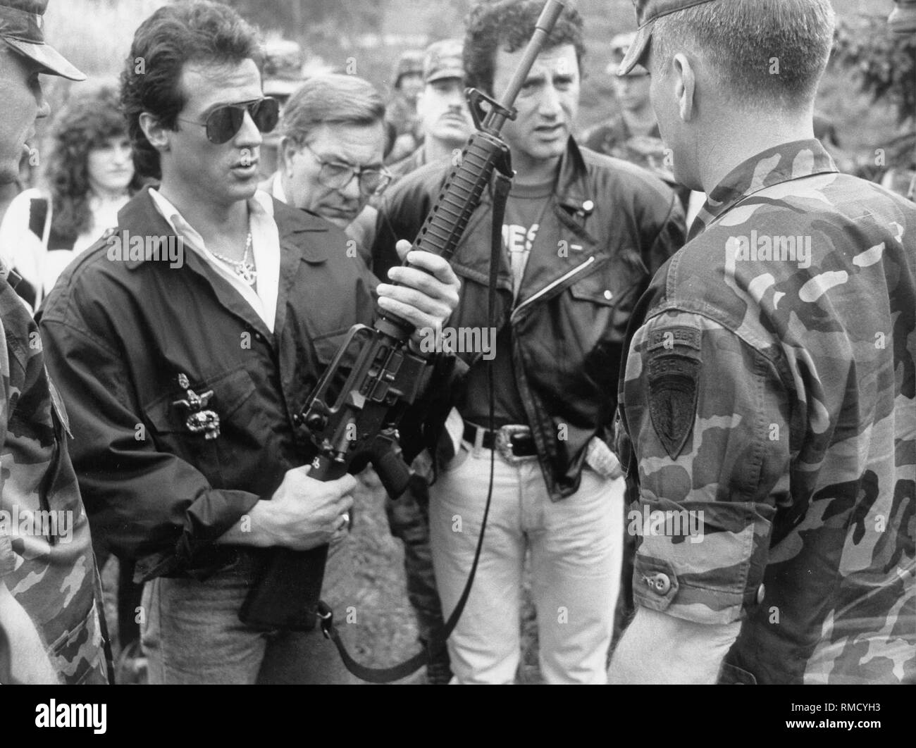 Der Schauspieler Sylvester Stallone Besuche amerikanischer Truppen in Berlin und hier verarbeitet eine M-16 Sturmgewehr. Rechts von Sylvester im Hintergrund, sein Bruder Frank. Stockfoto