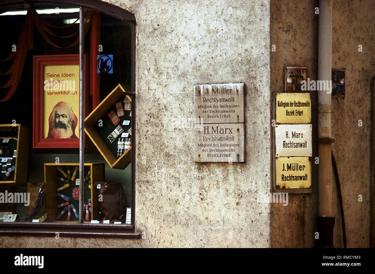 Detail einer Hausfassade in Erfurt: Auf der linken Seite ist ein Schaufenster mit einem Bild von Karl Marx mit dem Slogan 'seine Ideen, die wir verwirklichen wird", und auf der rechten das Typenschild des Rechtsanwalts H. Marx. Stockfoto