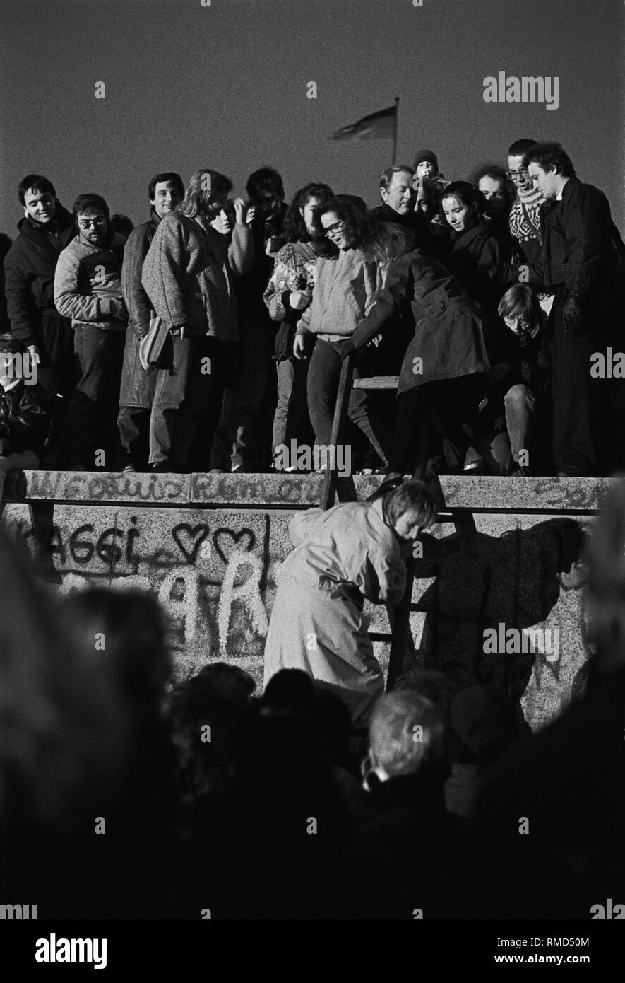 Fröhliche Festival auf der Mauer am Brandenburger Tor, Menschen aus Ost und West an der Wand stehen, einige sind nach oben klettern (Berlin), Berlin-Tiergarten, 10.11. 1989 Stockfoto