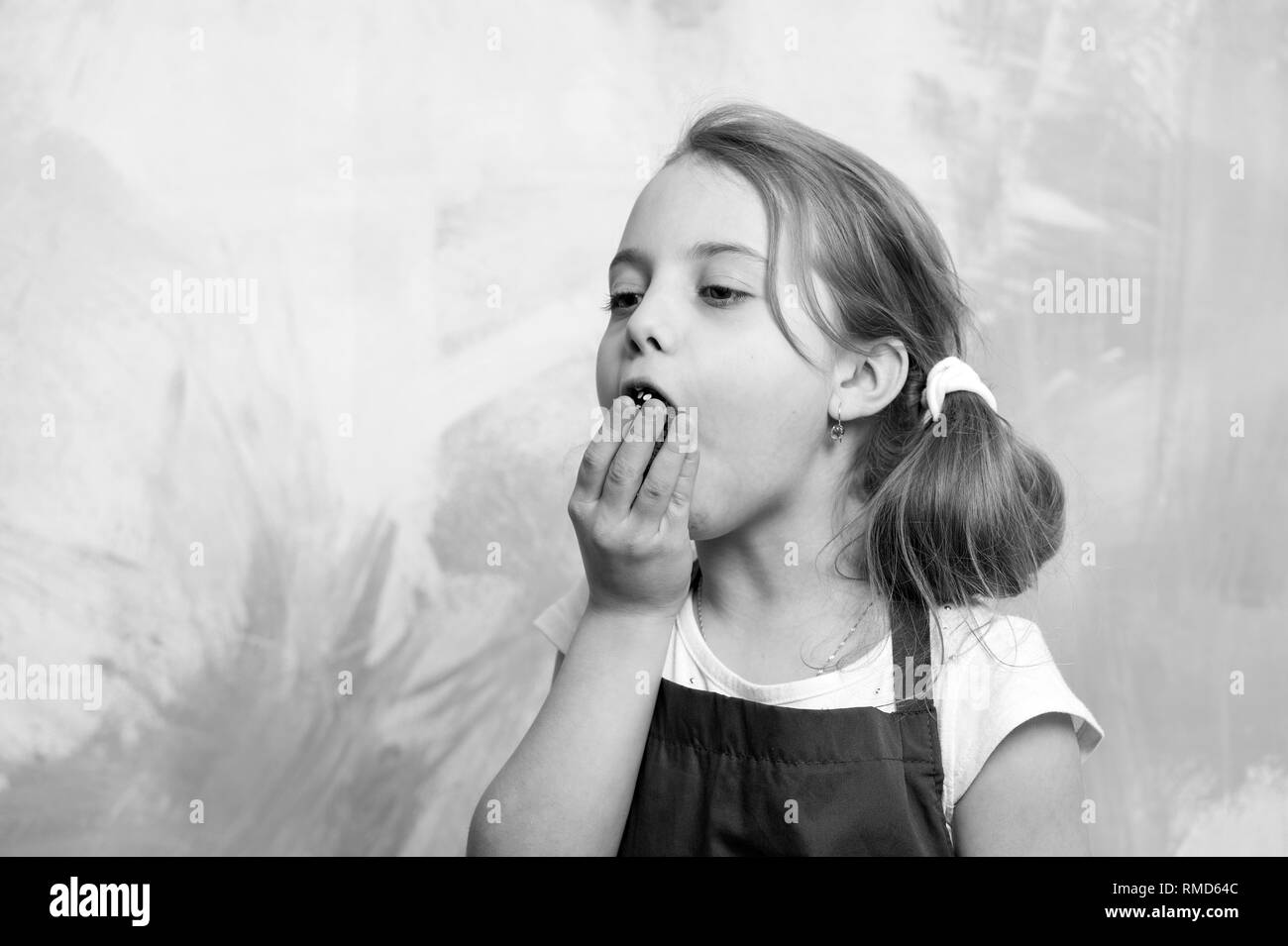 Chef Kind mit Cupcake. Kleine Mädchen auf farbigen Hintergrund. Kochen und Essen. Kindheit und Ausbildung. Kind in Koch Schürze. Essen süchtig Stockfoto