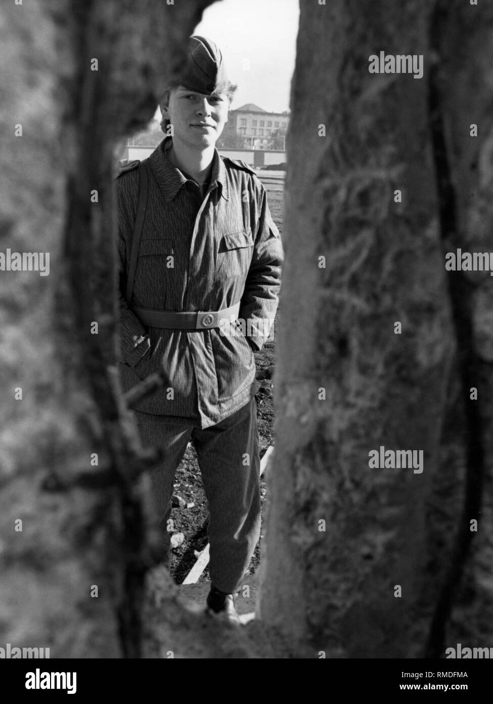 Ein Mitglied der Grenze Truppe hinter einem Loch in der Wand nach der Öffnung der Berliner Mauer. Stockfoto