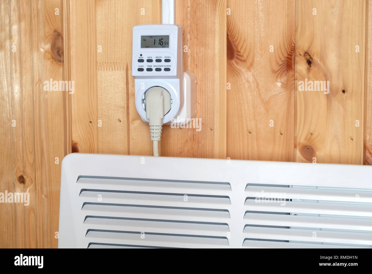 Arbeiten weiß elektrischer Konvektor Heizung angeschlossen, um timer Steckdose im Smart house System gegen hölzerne Wand im Zimmer Seitenansicht closeup betrieben Stockfoto