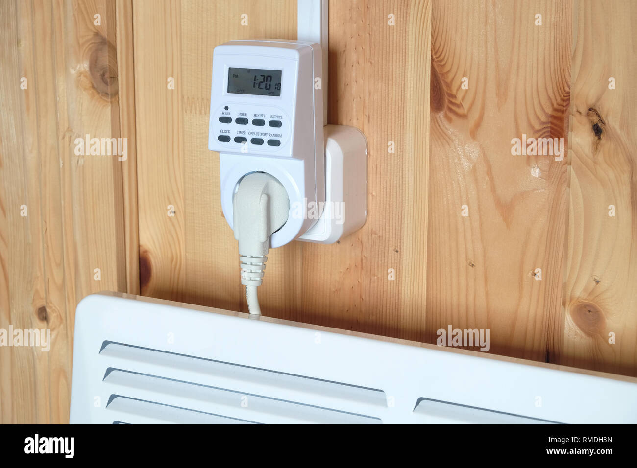 Arbeiten weiß elektrischer Konvektor Heizung angeschlossen, um timer Steckdose im Smart house System gegen hölzerne Wand im Zimmer Seitenansicht closeup betrieben Stockfoto