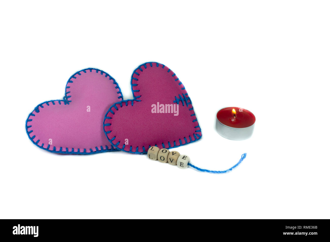 Gebrauchte Textilmaschinen Herzen mit dem Wort Liebe auf Blöcken auf Strings auf weißem Hintergrund für eine romantische Beziehung isoliert mit Gewinde genäht, Valentinstag, Brok Stockfoto