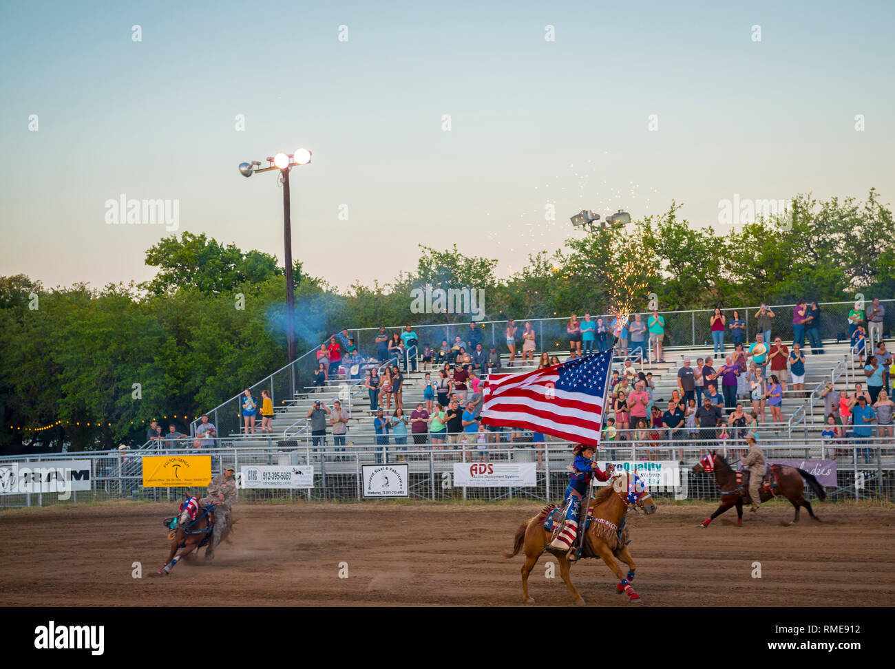 Cowgirl Reiten mit amerikanischer Flagge während Rodeo Stockfoto