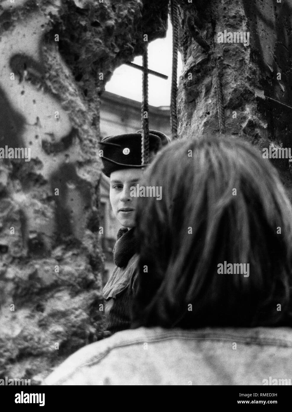 West Berlin und DDR-Grenzsoldaten Blick durch ein Loch in der Wand. Stockfoto