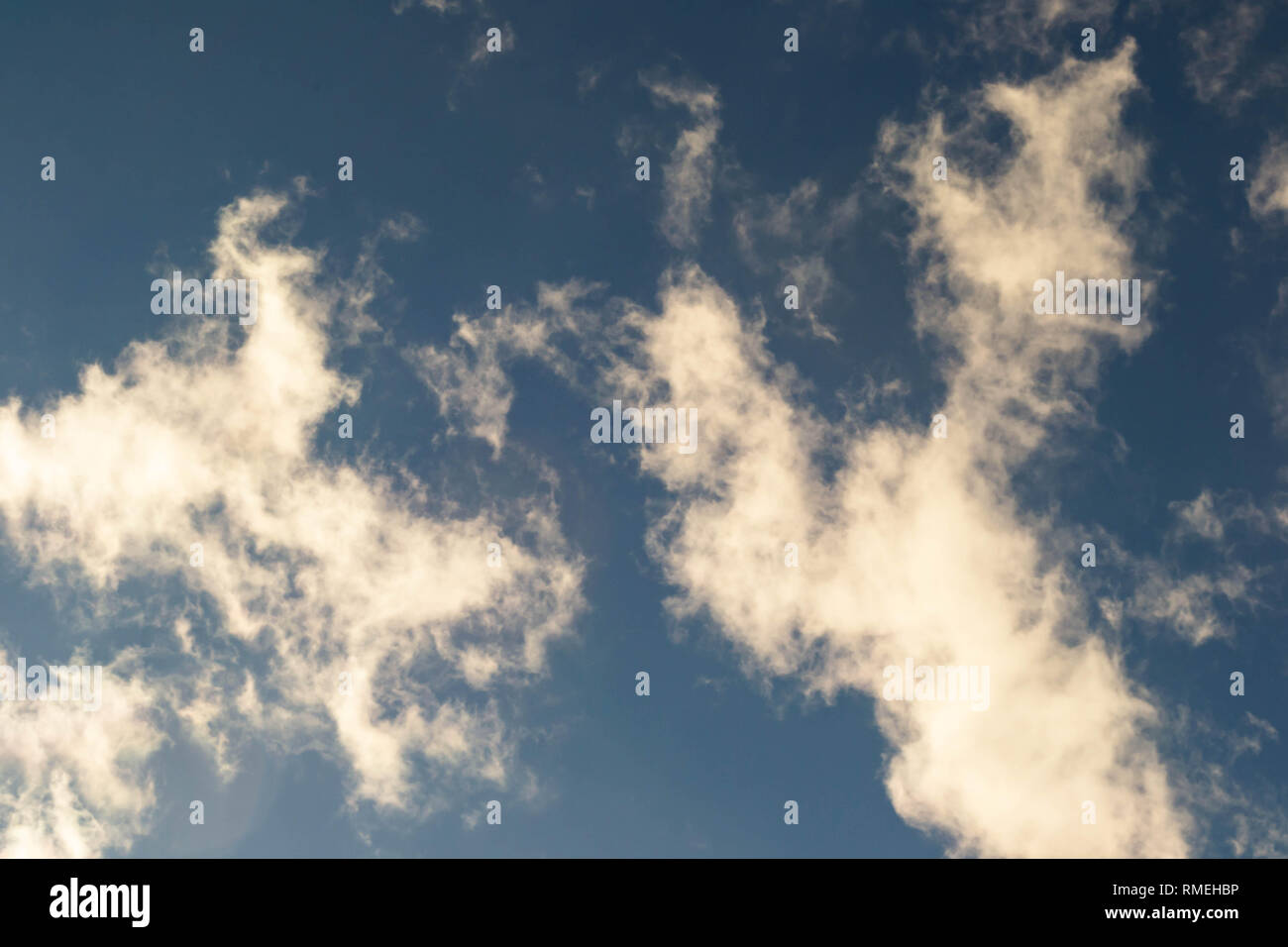 Smoky Wolken schweben über einer blauen Nachmittag Himmel. Stockfoto