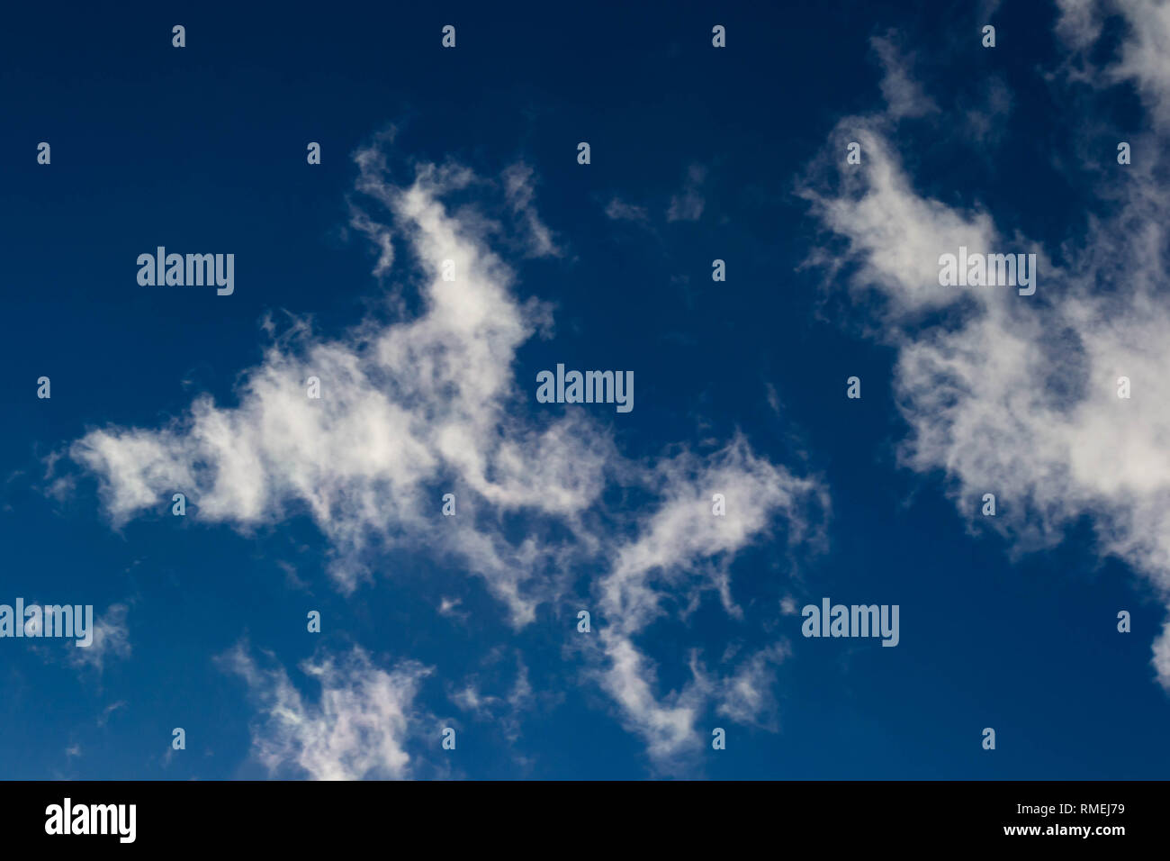 Smoky Wolken schweben über einer blauen Nachmittag Himmel. Stockfoto