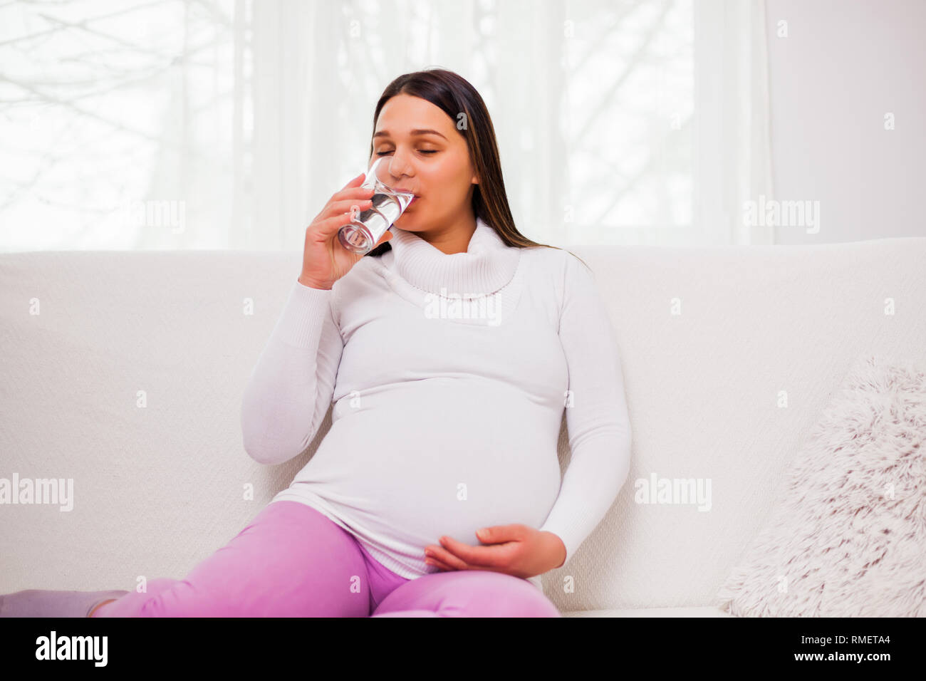 Schwangere Frau ist Trinkwasser. Stockfoto